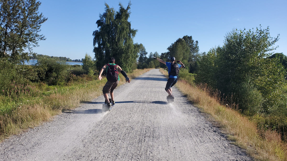 two men riding onewheel on a gravel trail